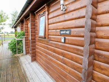 Exterior view of a wooden log cabin with a window a door and a sign that reads Heathcliff Lodge at Heathcliff in Northallerton