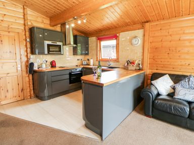 A kitchen with wooden countertops grey cabinets a black leather sofa and wooden walls at Heathcliff in Northallerton