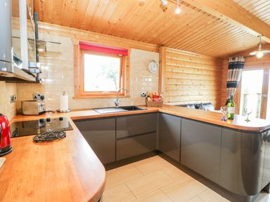 A kitchen with wooden countertops grey cabinets a window and various kitchen appliances at Heathcliff in Northallerton