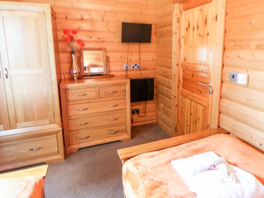 A wooden bedroom with dresser mirror television and wardrobe at Heathcliff in Northallerton