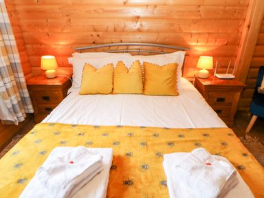 A bed with yellow pillows and blanket with two bedside tables with lamps in a wooden room at Heathcliff in Northallerton