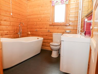 A bathroom with a bathtub toilet sink and a window with a floral blind at Heathcliff in Northallerton