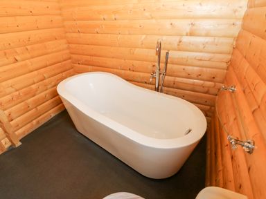 A wooden bathroom with a white freestanding bathtub and chrome faucet at Heathcliff in Northallerton