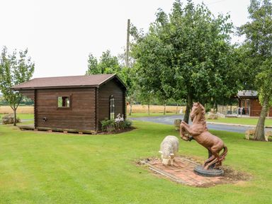 A garden with a wooden shed trees a horse statue and a sheep statue at Heathcliff in Northallerton