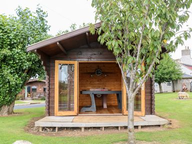 A wooden garden shed with open double doors showing a foosball table inside at Heathcliff in Northallerton