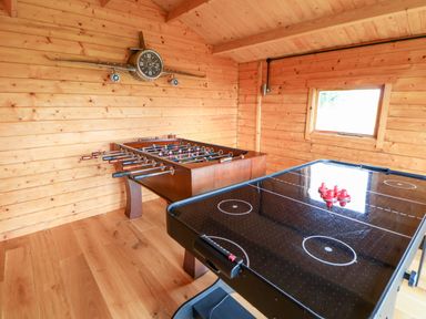 A game room with a foosball table and an air hockey table in a wooden cabin at Heathcliff in Northallerton
