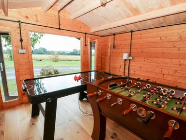 A game room with an air hockey table and foosball table in a wooden cabin at Heathcliff in Northallerton
