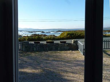 A view of a rocky coastline with water and hills seen through a window at Ti Sheamuis Cashel near Carna County Galway