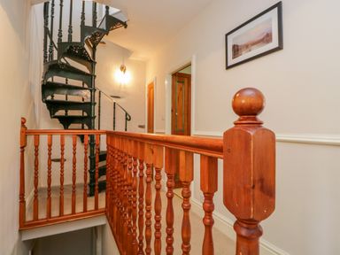 A hallway with wooden railing and a black spiral staircase at Fishers Retreat in Bowness-On-Windermere