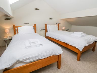A bedroom with two single beds with white bedding and towels on top at Fishers Retreat in Bowness-On-Windermere