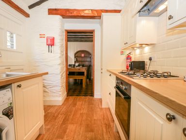 A kitchen with white cabinets wooden countertops a gas stove oven a toaster and a fire extinguisher at Fisher's Retreat in Bowness-On-Windermere