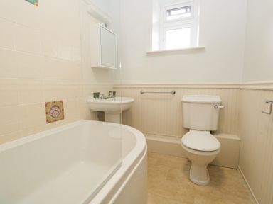 A bathroom with a bathtub sink toilet and a window at Fishers Retreat in Bowness-On-Windermere
