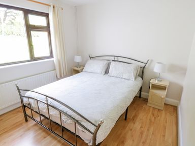 A bedroom with a metal bed frame two bedside tables and two lamps at Aras Iosgan in Carraroe County Galway