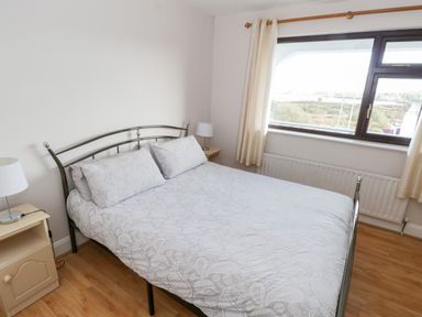 A bedroom with a double bed with patterned bedding and two side tables with lamps at Aras Iosgan in Carraroe County Galway