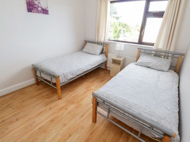 A bedroom with two single beds a nightstand and lamp under a window at Aras Iosgan in Carraroe County Galway