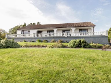 A house with a tiled roof a white balustrade and a garden in front at Aras Iosgan in Carraroe County Galway