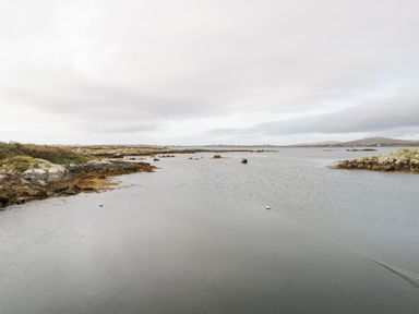 A coastal scene with rocky shores and calm water at Aras Iosgan in Carraroe County Galway