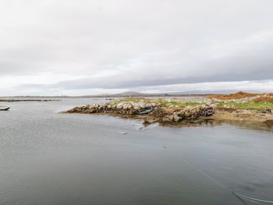 A coastal scene with rocky shoreline and small boats near the water at Aras Iosgan in Carraroe County Galway
