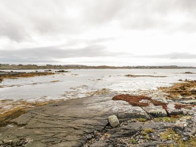 A rocky shoreline with seaweed and water under a cloudy sky at Aras Iosgan in Carraroe County Galway