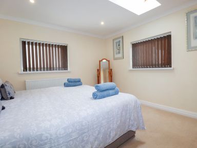 A bedroom with a large bed with blue towels on it and two windows with vertical blinds at Chapel Green Studio 2 in Polgooth