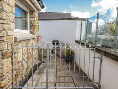 An outdoor patio with a gate and seating area at Chapel Green Studio 2 in Polgooth