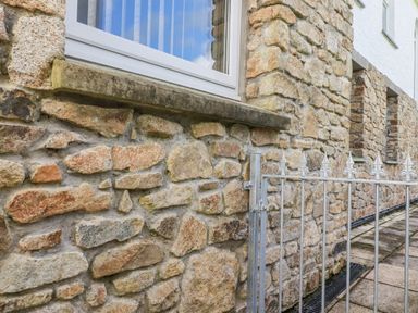 A stone wall with a window and a metal gate at Chapel Green Studio 2 in Polgooth