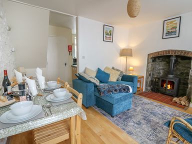 A living room with a blue sofa a dining table set with bowls and glasses and a fireplace at Rowan Cottage in Builth Wells