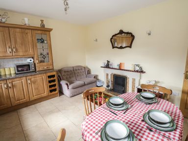 A kitchen dining area with wooden cabinets a dining table set with plates a sofa and a fireplace at Belladrihid Cottage Ballysadare near Sligo County Sligo