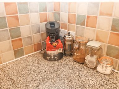 A kitchen countertop with a coffee machine a french press and three jars with tea coffee and sugar at Cowslip Barn Cornworthy near Dittisham