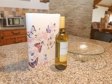 A kitchen counter with a bottle of white wine book with butterfly design and a glass bowl at Cowslip Barn in Cornworthy near Dittisham