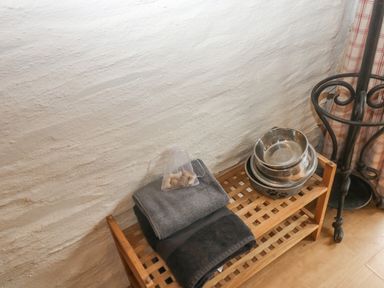 A wooden bench holding folded towels a small bag of dog treats and stacked pet bowls at Cowslip Barn Cornworthy near Dittisham