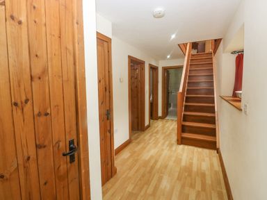 A hallway with wooden doors wooden staircase and light wood flooring at Cowslip Barn in Cornworthy near Dittisham