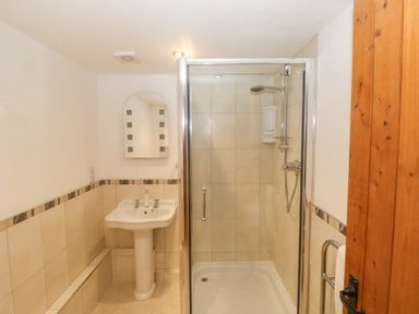 A bathroom with a pedestal sink mirror and a glass-enclosed shower at Cowslip Barn in Cornworthy near Dittisham
