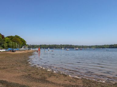 A shoreline with boats on the water and boats lined up on the shore at Cowslip Barn in Cornworthy near Dittisham