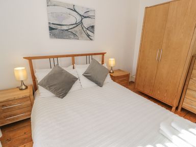 A bedroom with a double bed two bedside tables with lamps a wardrobe and a chest of drawers at Snowdon View in Llanberis