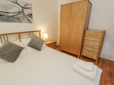 A bedroom with a bed pillows folded towels bedside table lamp wardrobe and chest of drawers at Snowdon View in Llanberis