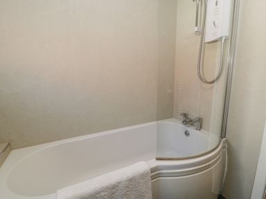 A bathroom with a bathtub a shower unit and a towel on the edge at Snowdon View in Llanberis