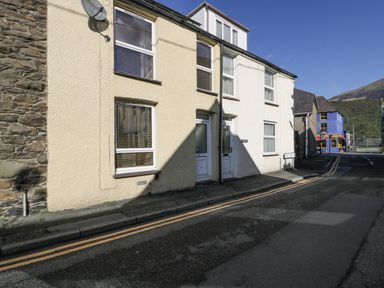 A street view of terraced houses with windows and doors on a sunny day at Snowdon View in Llanberis