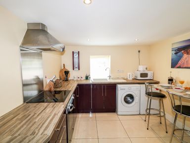 A kitchen with countertop stove sink washing machine microwave and two high chairs at Whispering Willows - The Thatch in Carndonagh County Donegal