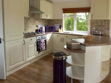 A kitchen with cream cabinets a countertop with appliances and a window at Morgan Lodge in Hewish near Weston-super-Mare