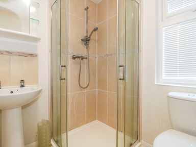 A bathroom with a glass shower enclosure a white sink with taps and a toilet near a window with blinds at Harvester Lodge in Hewish near Weston-super-Mare