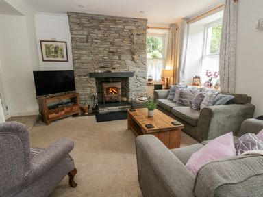 A living room with a stone fireplace and sofas at Teifi House in Cilgerran near Cardigan
