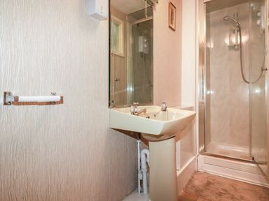 A bathroom with a pedestal sink a mirror a shower enclosure and a towel rail at The Ark Cottage in St Blazey