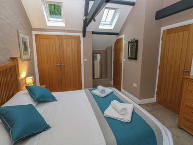 A bedroom with a double bed with blue pillows and towels on the bed and wooden doors at Stable Cottage in Pembroke
