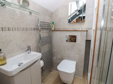 A bathroom with a sink vanity a towel radiator a wall-mounted toilet and a shower at Stable Cottage in Pembroke