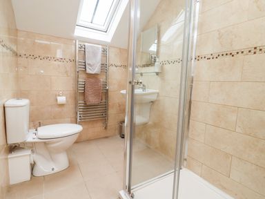 A bathroom with a toilet sink shower and towel rack under a skylight at Cow Byre Great Tew near Chipping Norton