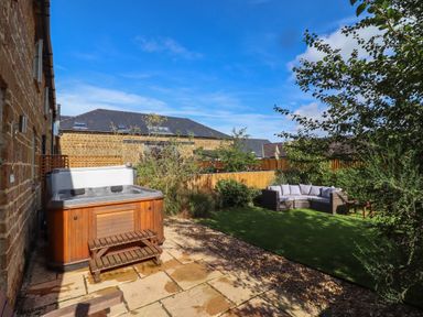 A garden with a hot tub patio and outdoor seating at The Stables in Great Tew near Chipping Norton
