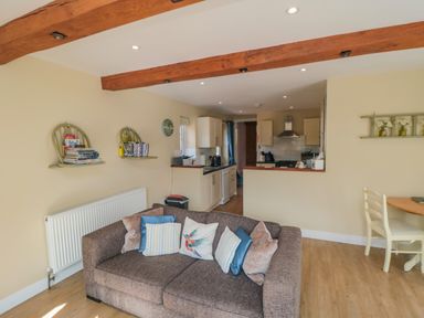 A living room with a sofa and cushions near an open kitchen and dining area at Ericas eaven in Farndale near Kirkbymoorside