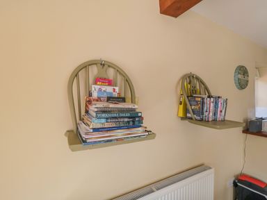 Two wall shelves made from chair backs holding books and DVDs in a room at Ericas eaven in Farndale near Kirkbymoorside