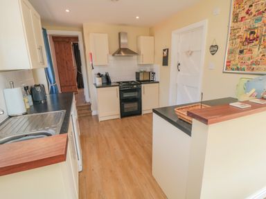 A kitchen with cream cabinets black countertops a stove a microwave and a wooden floor at Ericas eaven in Farndale near Kirkbymoorside